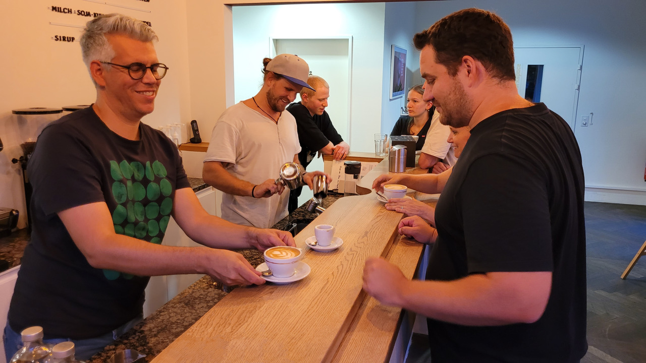 Chef-Barista und Sozialpädagoge Ermanno Vattolo serviert Geschäftsleiter Philipp Nussbaumer (vorne rechts) einen Cappuccino. «Die Kaffeebar ist unser Dorfbrunnen», sagt Nussbaumer. Foto: sd